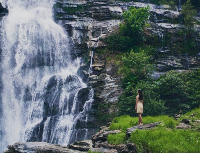 fascinating-low-angle-shot-female-admiring-waterfall-doi-inthanon-park-thailand_181624-4883